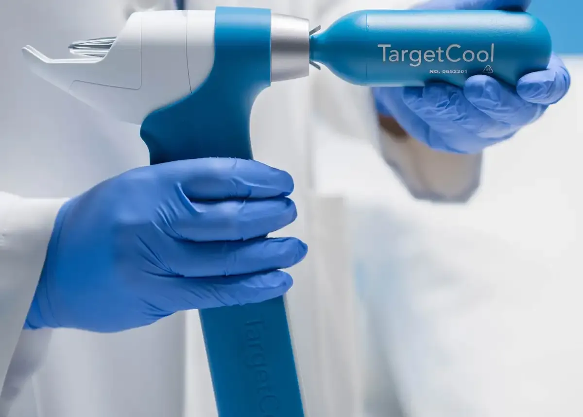 Aplicación del dispositivo TargetCool en la zona del rostro de una paciente mientras se realiza un procedimiento médico.