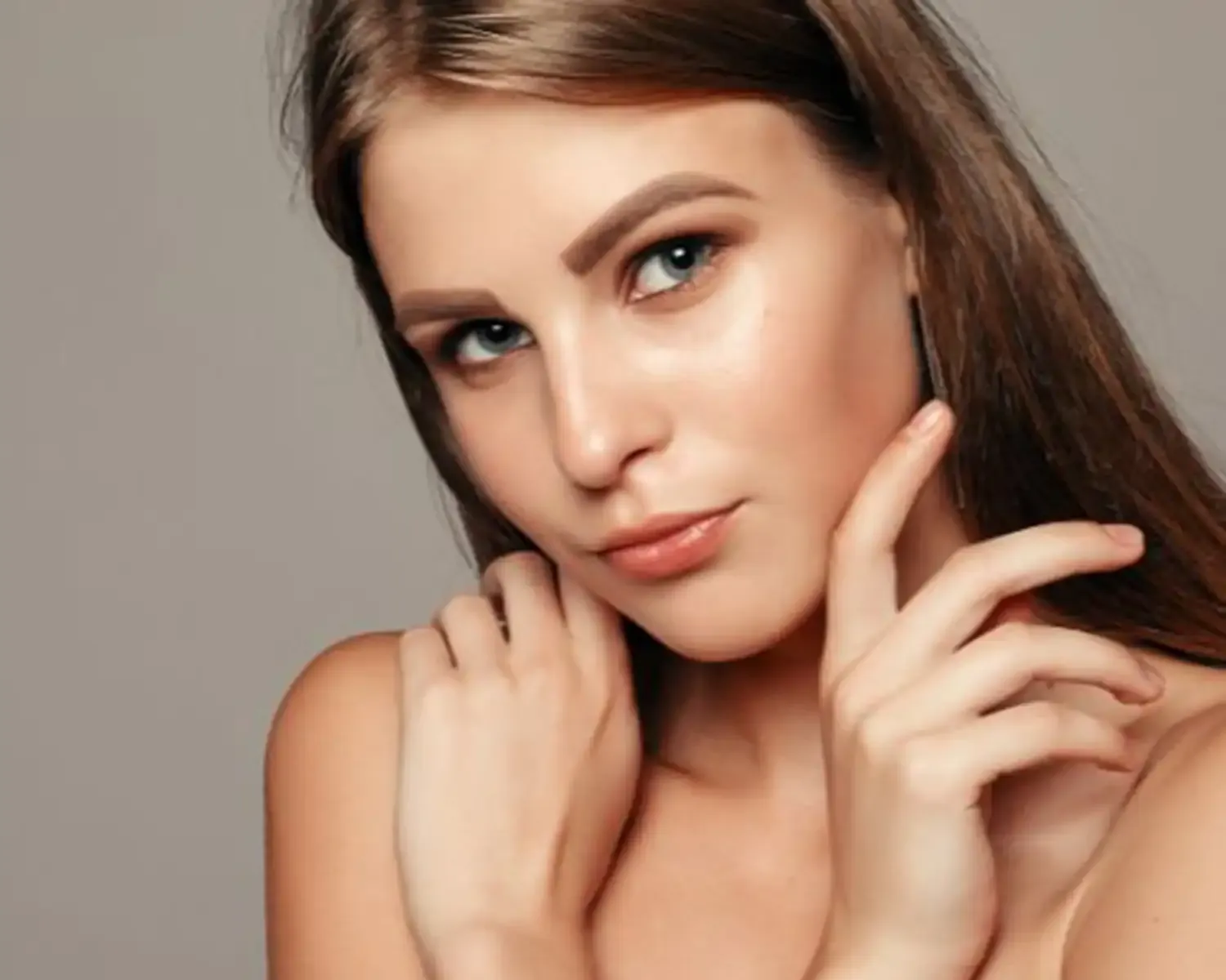 Mujer con cabello castaño claro tocándose el rostro con la mano.