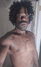 Black man with clean cut facial hair short dreads dress as Goku